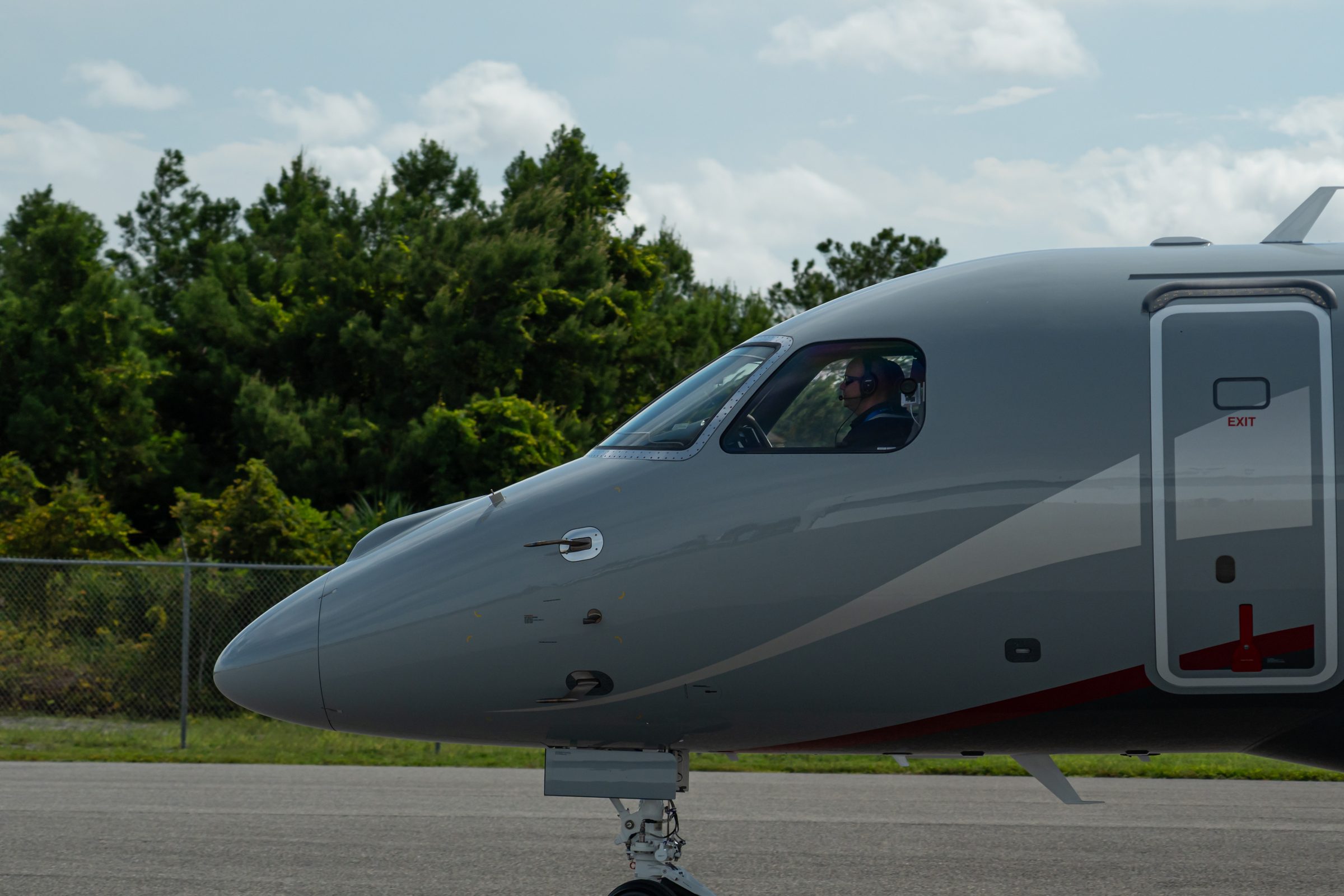 Business jet taxiing on the ramp past a line of trees