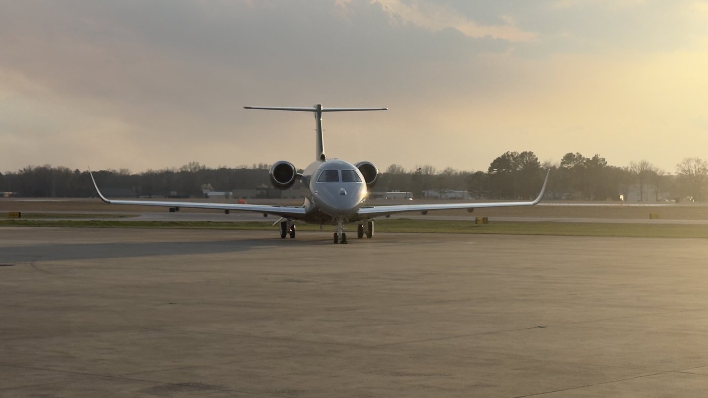 Embraer business jet facing the camera on the ramp at sunset